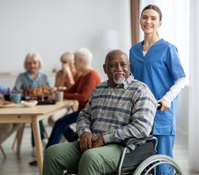 Happy older patient on wheelchair with female nurse