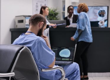 Medical assistant analyzing brain animation on laptop